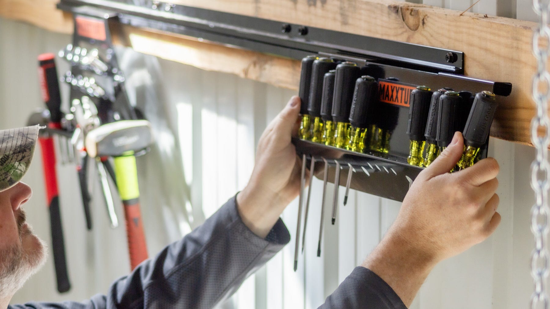 Man hanging the SwiftRaxx Screwdriver Organizer onto the SwiftRaxx wall mounting bracket